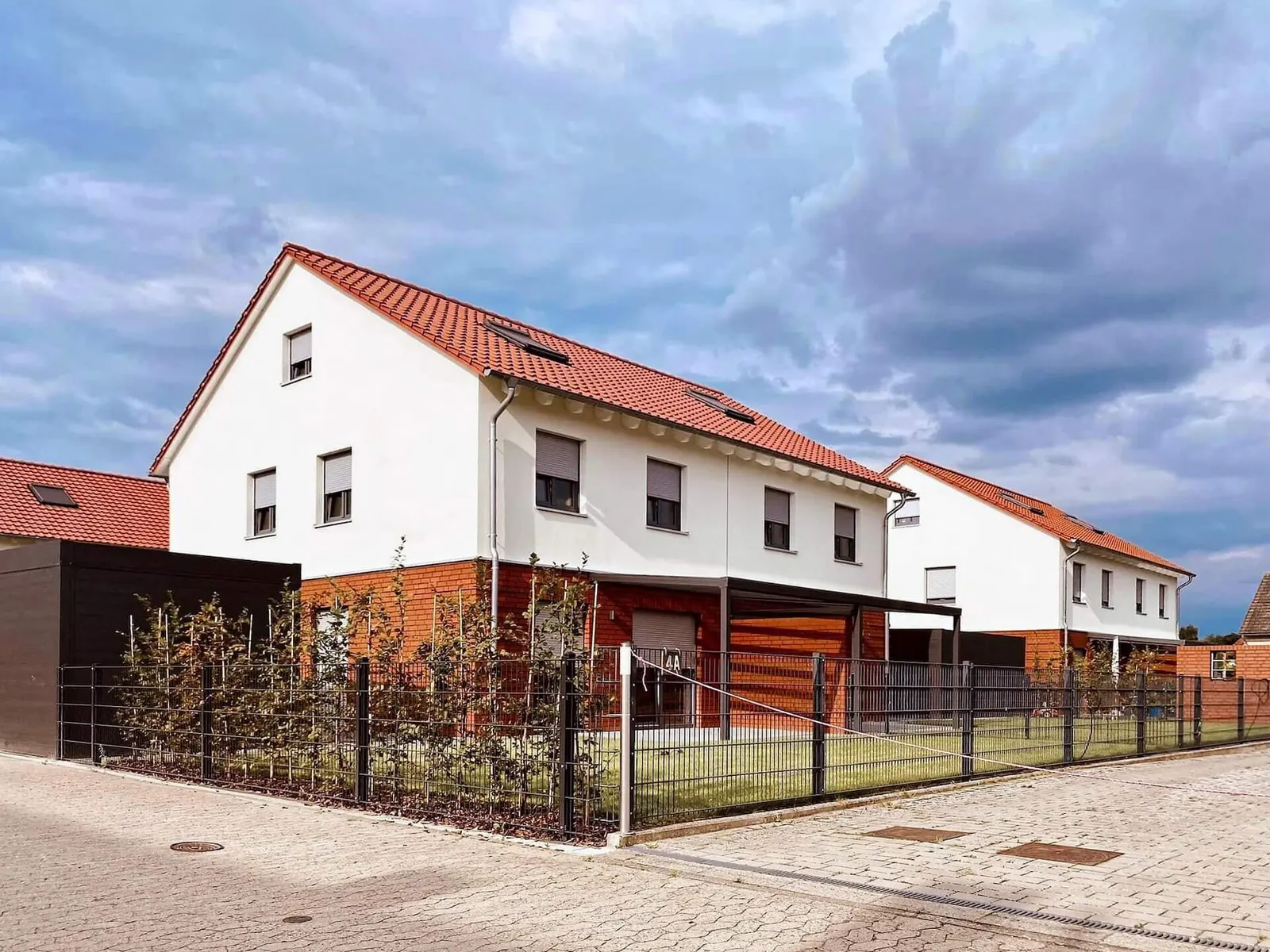 Neu gebaute Doppelhäuser mit roten Dächern und Carports