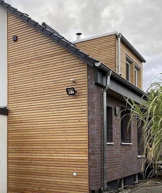 Anbau mit Holzfassade an einem Klinkergebäude